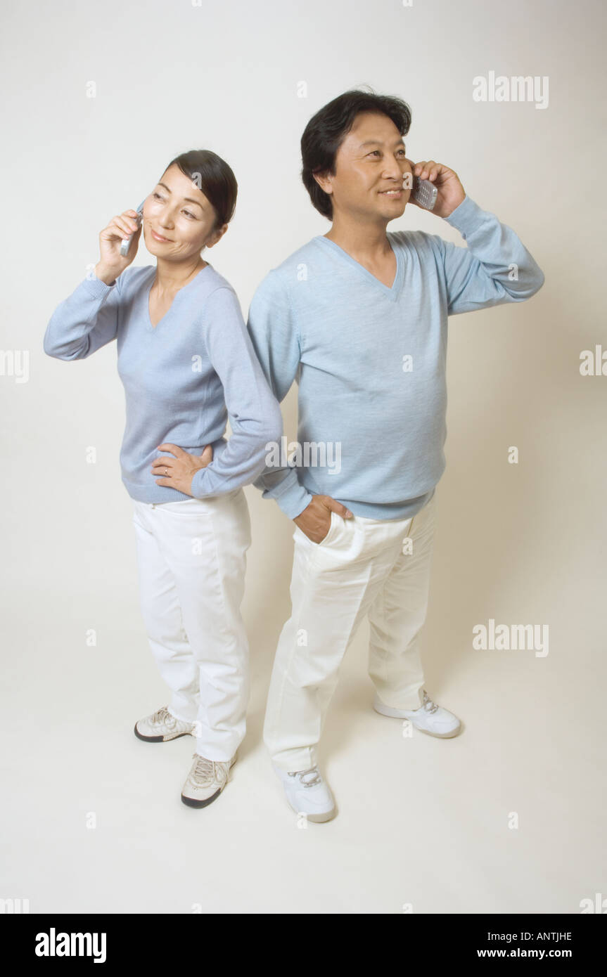 Coppia matura parlando su telefoni cellulari Foto Stock