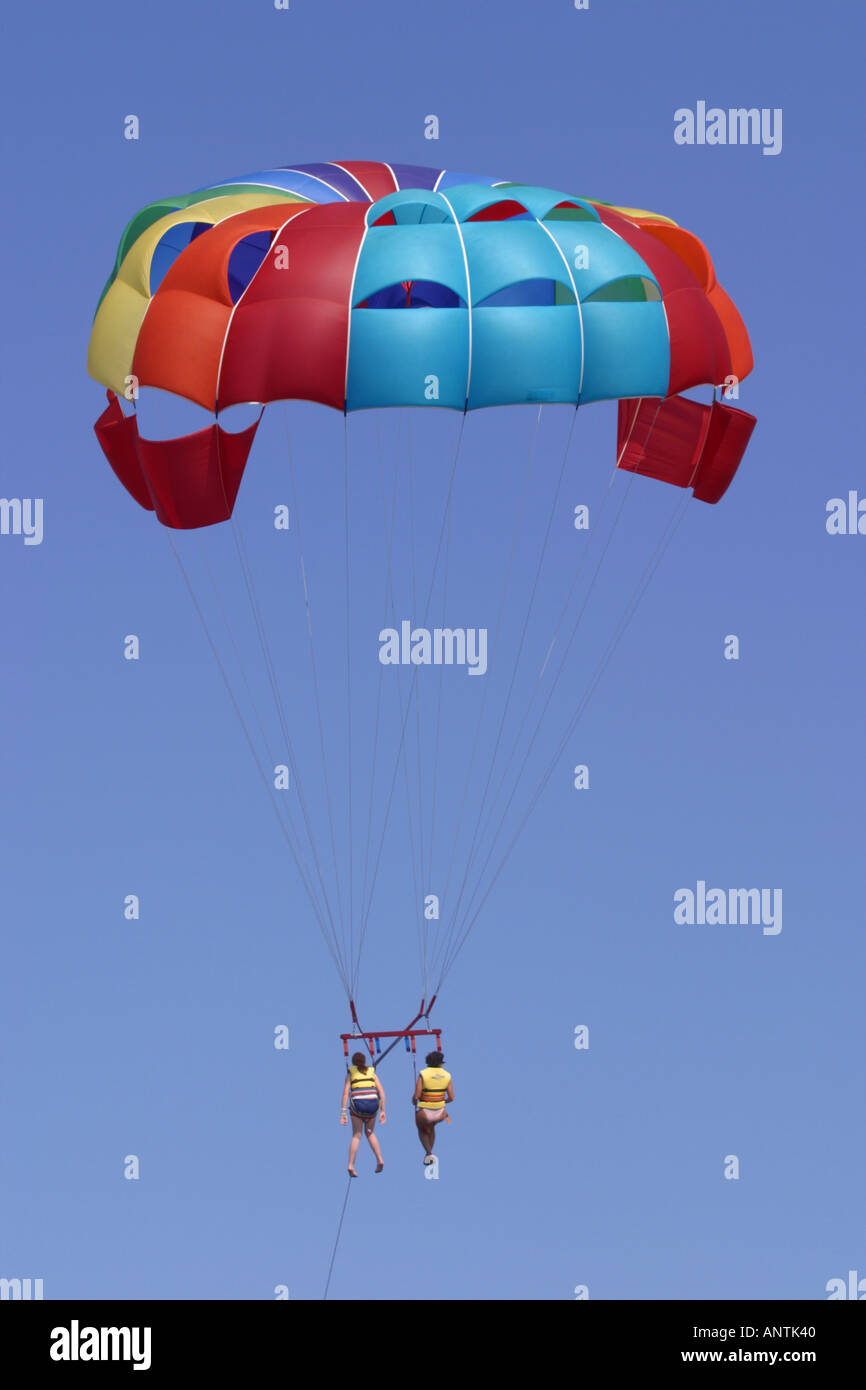Due persone condividono un giro con il paracadute trainato dietro un motoscafo in vacanza Foto Stock