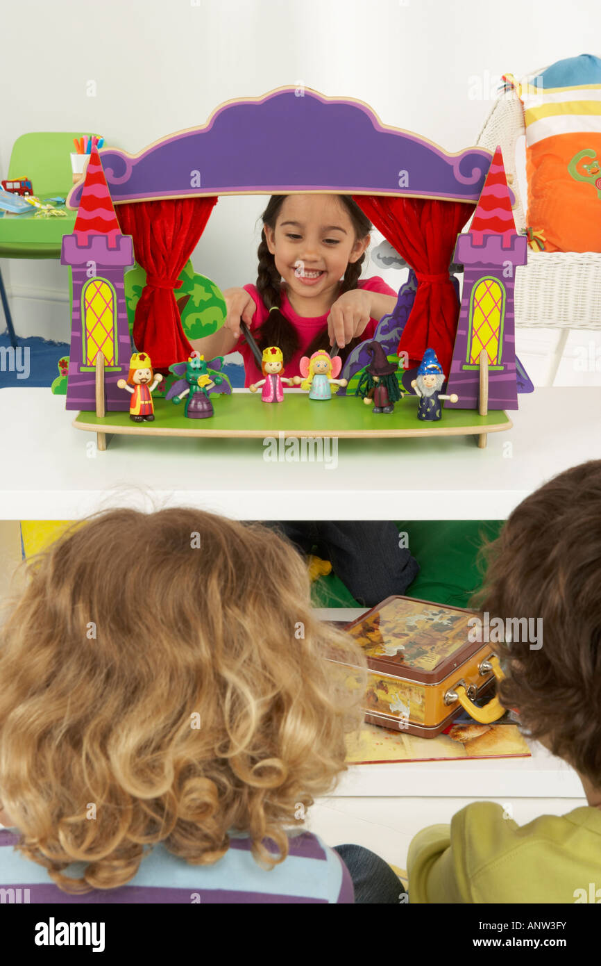 Una ragazza mette su un gioco utilizzando marionette a mano come i suoi due amici seduti tra il pubblico Foto Stock