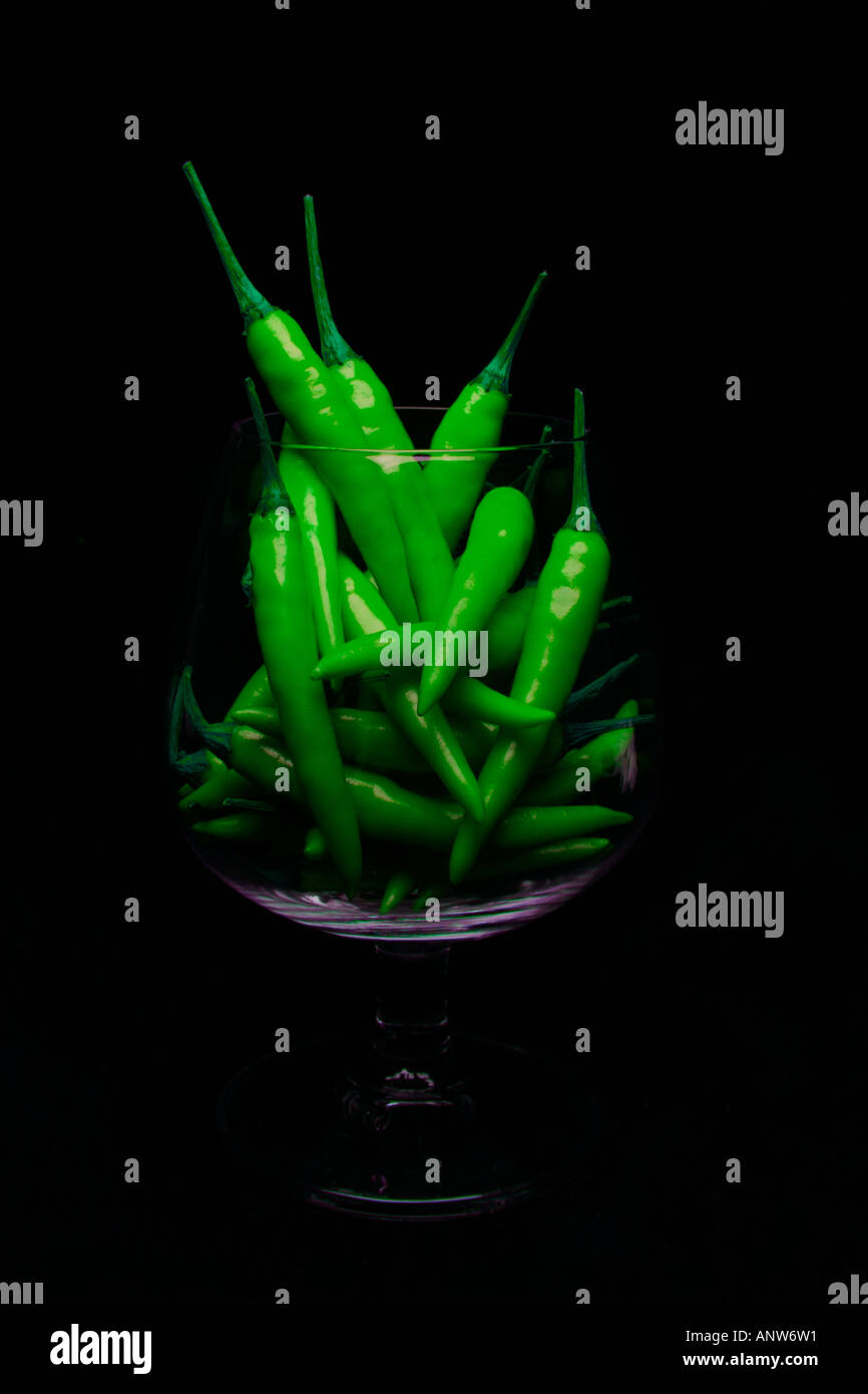 Hot luminose peperoncini verdi riempimento bicchiere di brandy di ritrarre una bevanda calda Foto Stock
