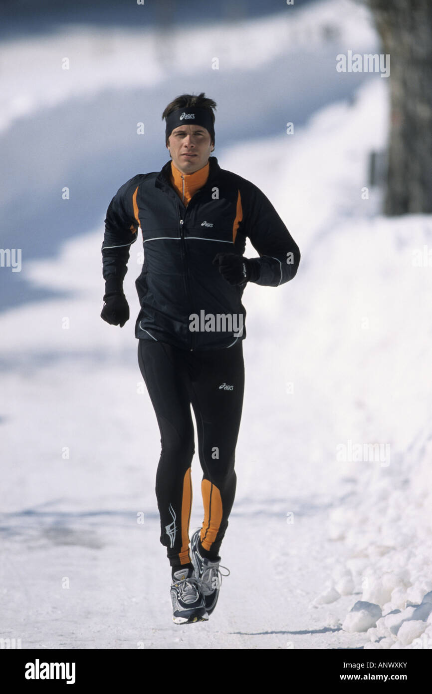 Un uomo jogging nella neve, Alpi Foto Stock