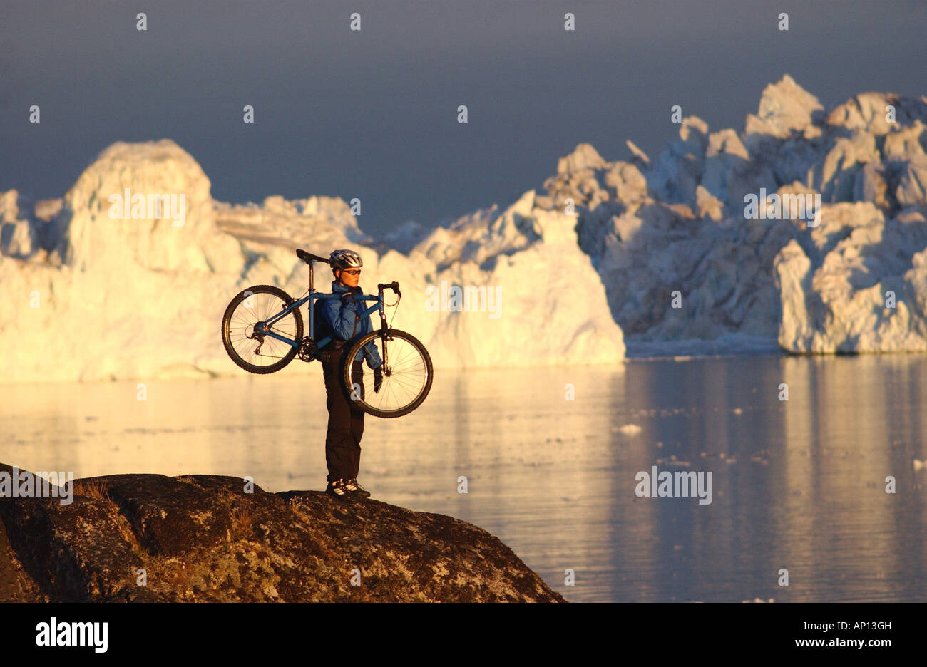 Femmina mountainbiker portando la sua bici, ammirando le viste, Ilulissat Foto Stock