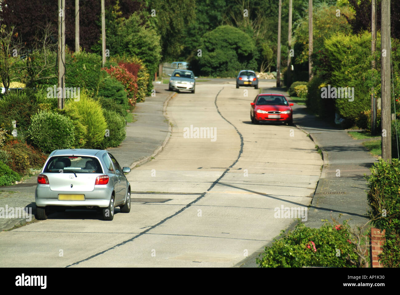 Essex village strada residenziale che mostra poche auto in strada con le case indietro dalla strada e passi carrai schermato dalla vegetazione Foto Stock