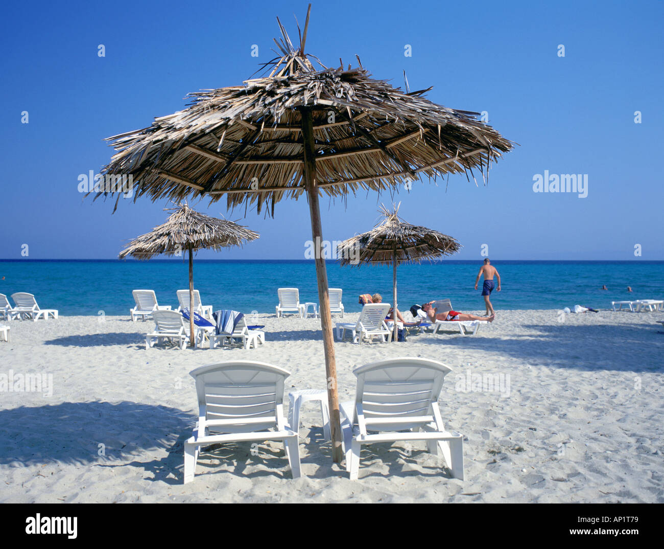 Spiaggia di Santorini, Grecia con secchi di foglie di palma utilizzato come sole ombre e il blu del mare e cielo senza nuvole Foto Stock