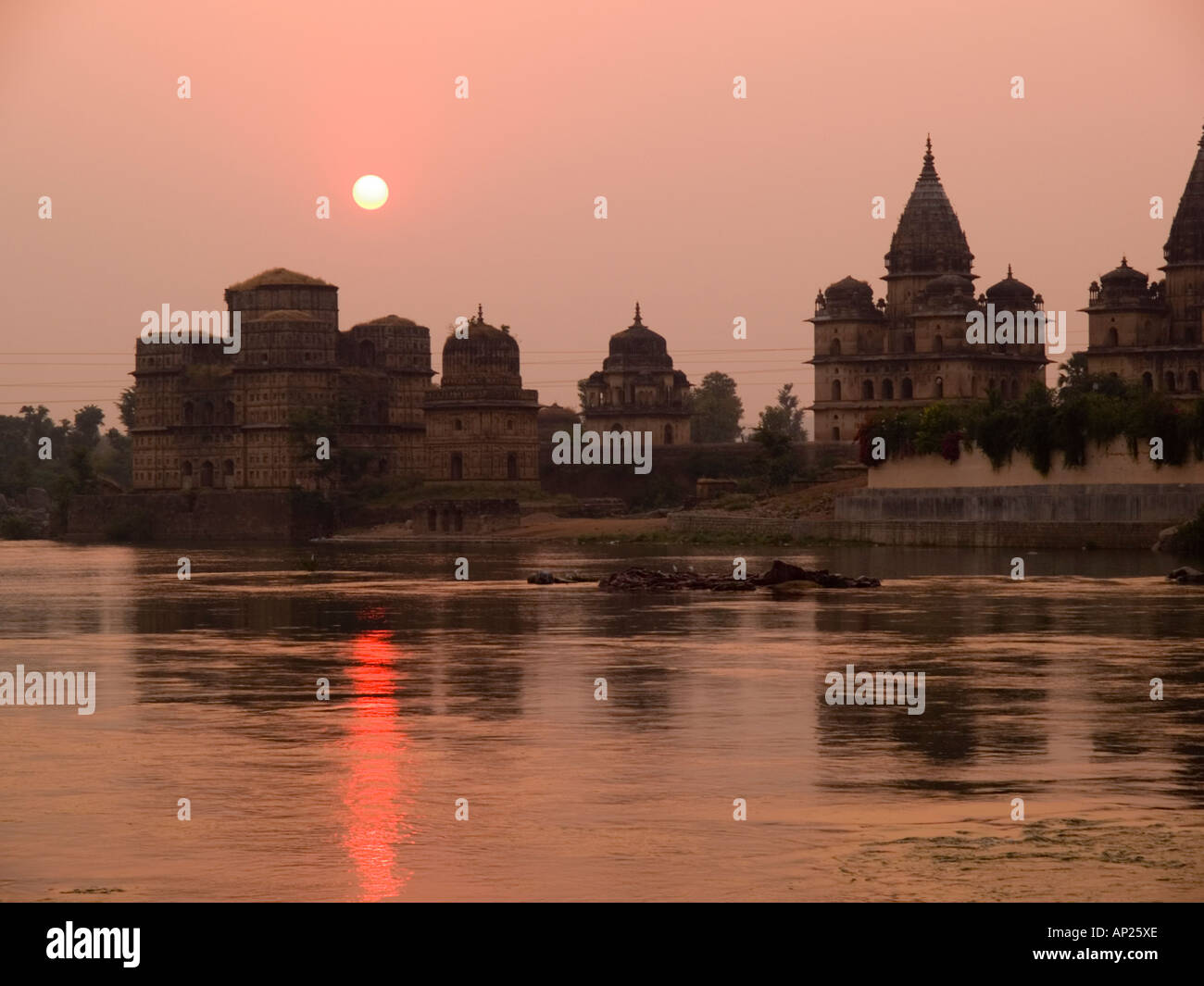 Orchha Madhya Pradesh India. Fiume Betwa al tramonto con il sole che tramonta dietro le cupole e guglie di Chhatris Bundela Foto Stock
