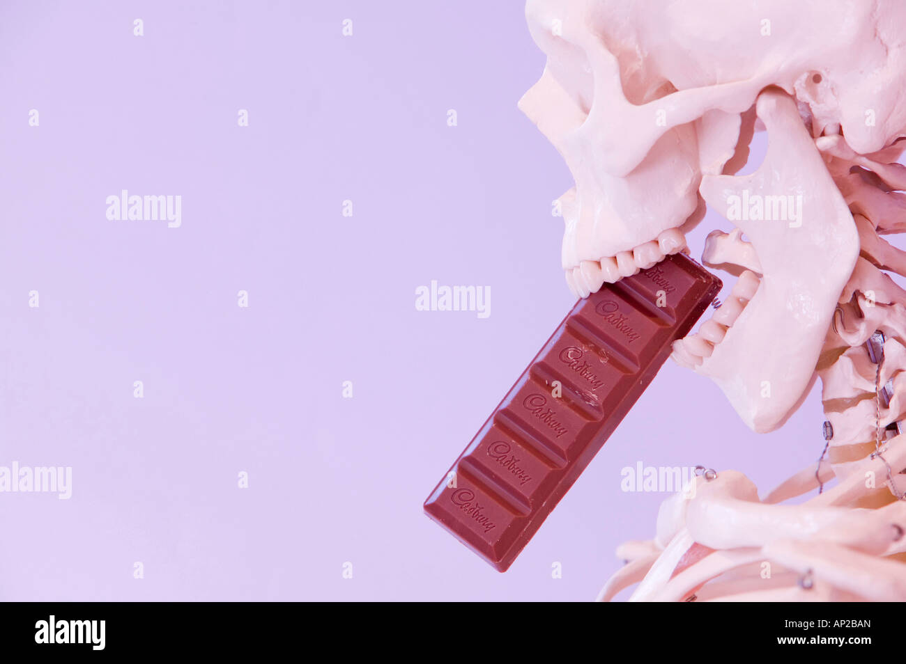 Uno scheletro umano a mangiare una barretta di cioccolato Foto Stock