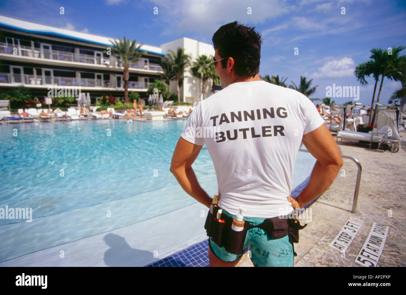 Giovane uomo in piedi presso la piscina di Hotel Ritz Carlton nella luce del sole, South Beach, Miami, Florida, Stati Uniti d'America Foto Stock