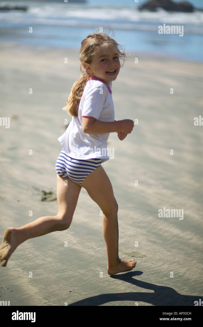 Ragazza che corre sulla spiaggia della piccola baia Okains a bassa marea, Okains Bay, Banca della penisola, east coast, Isola del Sud, Nuova Zelanda Foto Stock