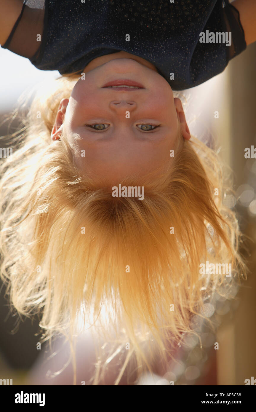 Ragazza giovane appeso a testa in giù nel parco giochi in una giornata autunnale Foto Stock