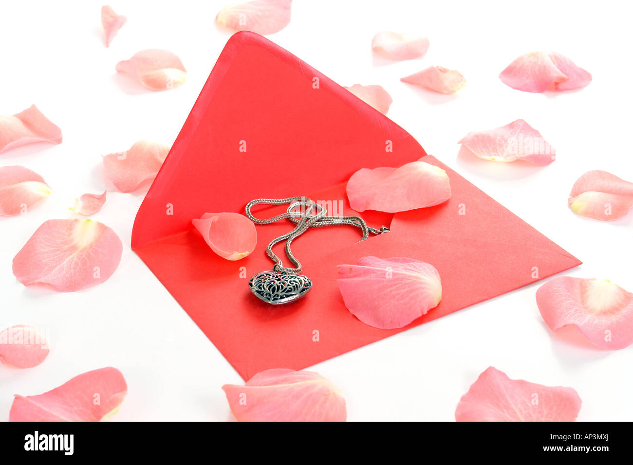 Busta rossa con heart-shaped necklet circondato da rosa sparsi petali di rosa Foto Stock