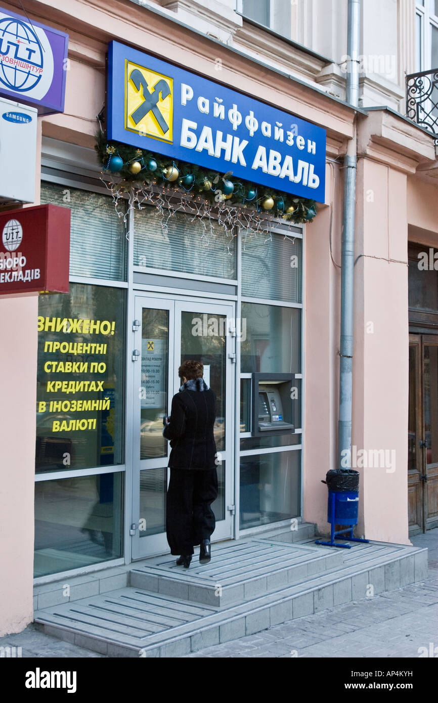Una donna va all'interno di una banca Raiffeisen Aval filiale a Kiev, Ucraina Foto Stock