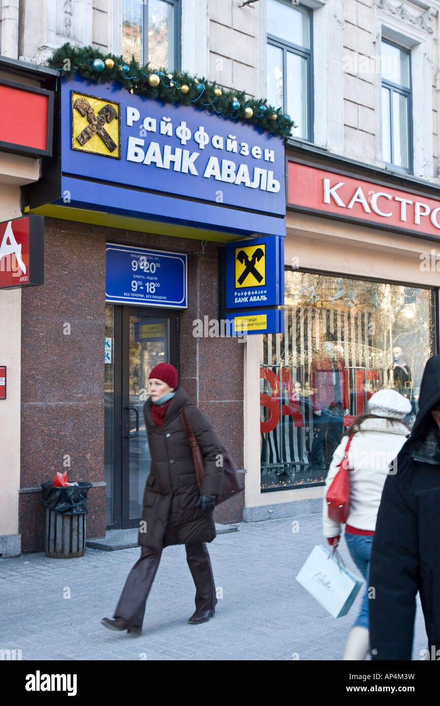 Una donna passa passa una banca Raiffeisen Aval filiale a Kiev, Ucraina Foto Stock