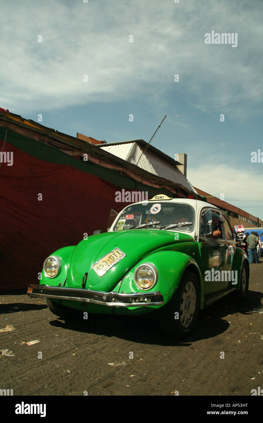 Un verde Volkwagen Beetle taxi trascina lungo una stretta strada laterale a Città del Messico Foto Stock