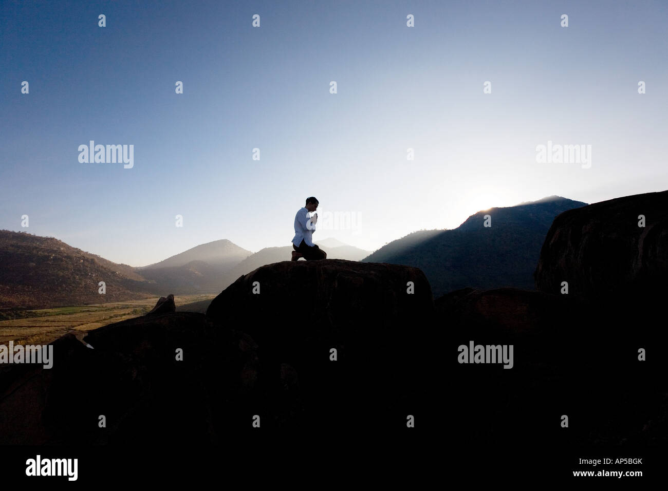 Silhouette di un uomo che prega su un Indiano mountain top di sunrise Foto Stock