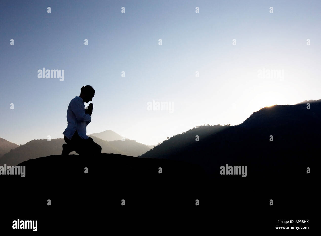 Silhouette di un uomo che prega su un Indiano mountain top di sunrise Foto Stock