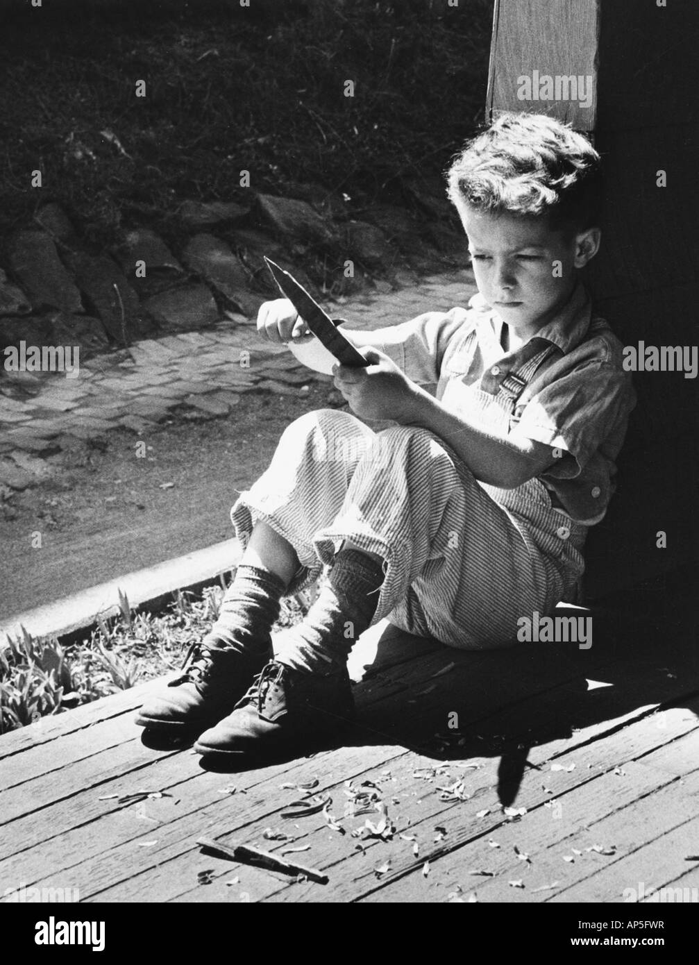 Ragazzo whilttling un bastone Foto Stock