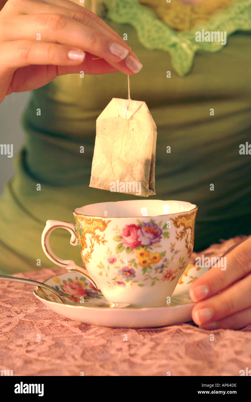 Mano con cucchiaio svuotamento sacchetto da tè in tazza di tè Foto Stock