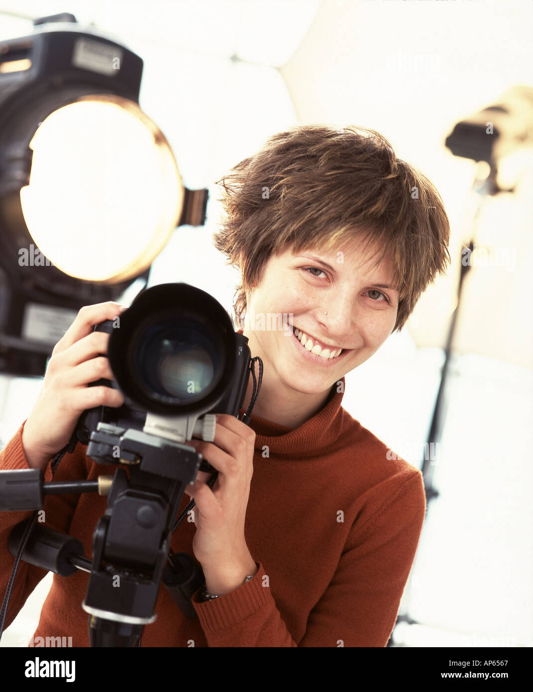 Giovane fotografo con il cavalletto montato fotocamera reflex e illuminazione professionale Foto Stock
