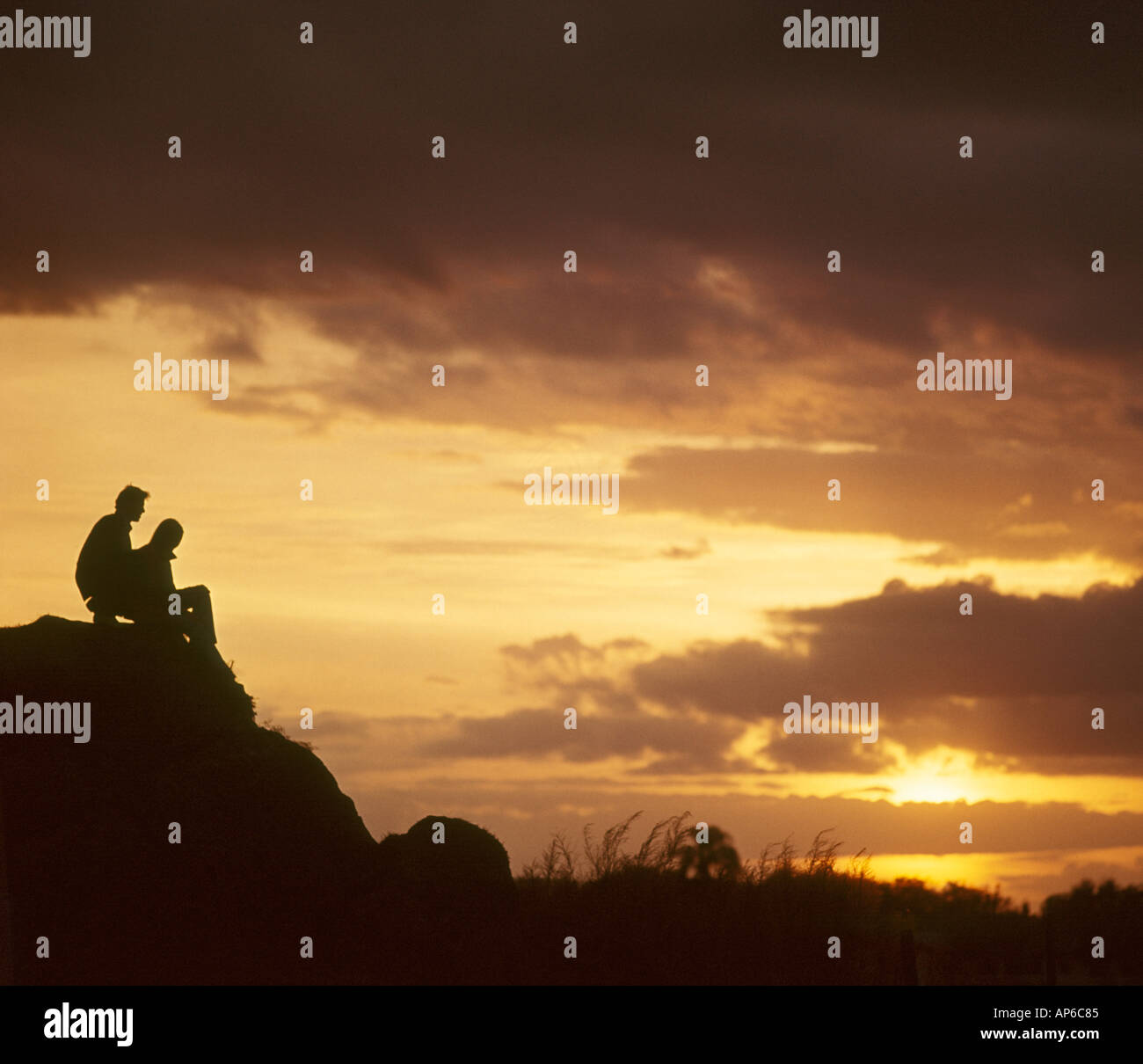 L uomo e la donna in relax sulla collina al tramonto Foto Stock