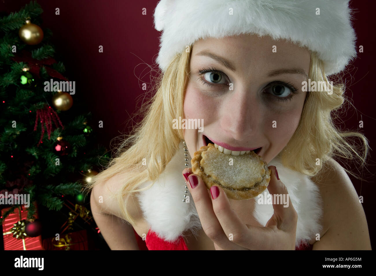La donna nel vestito festivo mangiare tritare la tradizionale torta decorata con albero in background Foto Stock