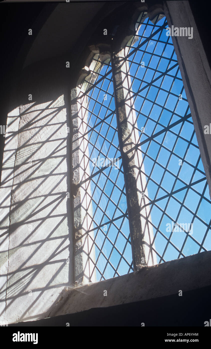 Visualizzare attraverso la pianura di diamante di vetro al piombo i riquadri della finestra all'inizio inglese in stile gotico di cielo blu con ombre Foto Stock