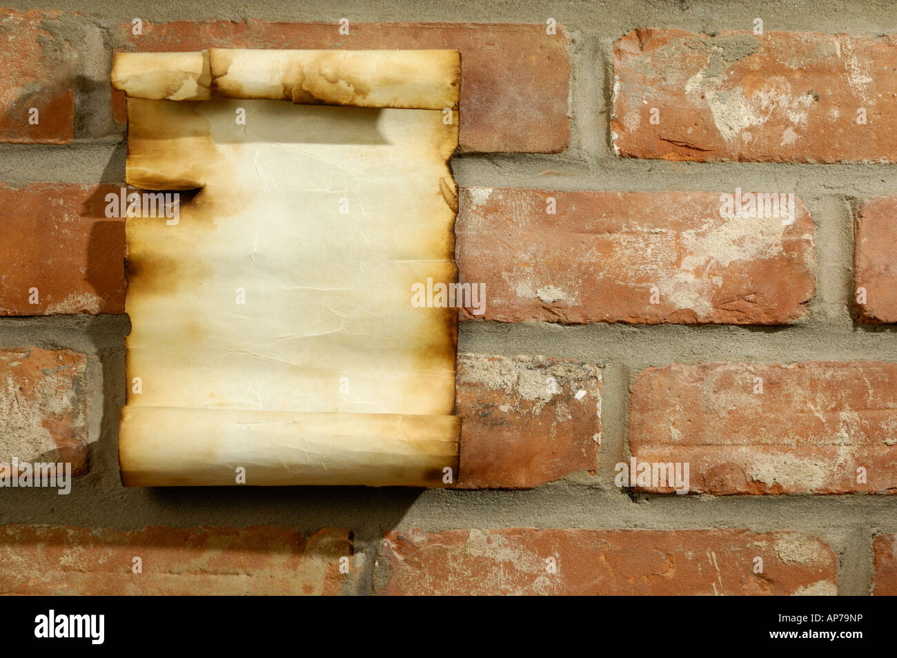 Vecchia pergamena con bordi masterizzato su un rosso muro di mattoni Foto Stock