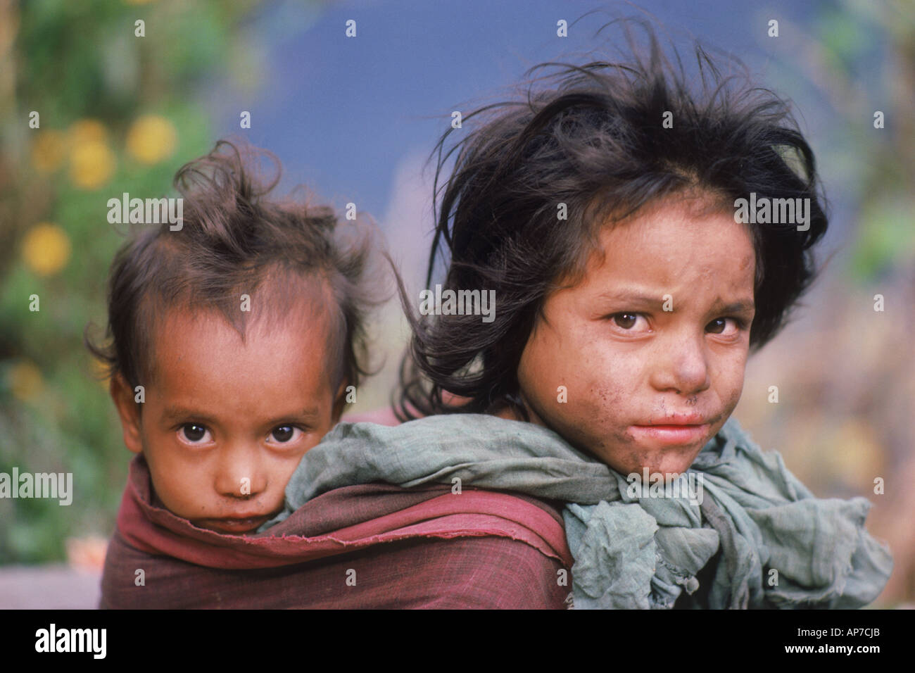 La ragazza che porta il suo bambino di un fratello o una sorella nel retro imbracare presso villaggio himalayano del Nepal Foto Stock