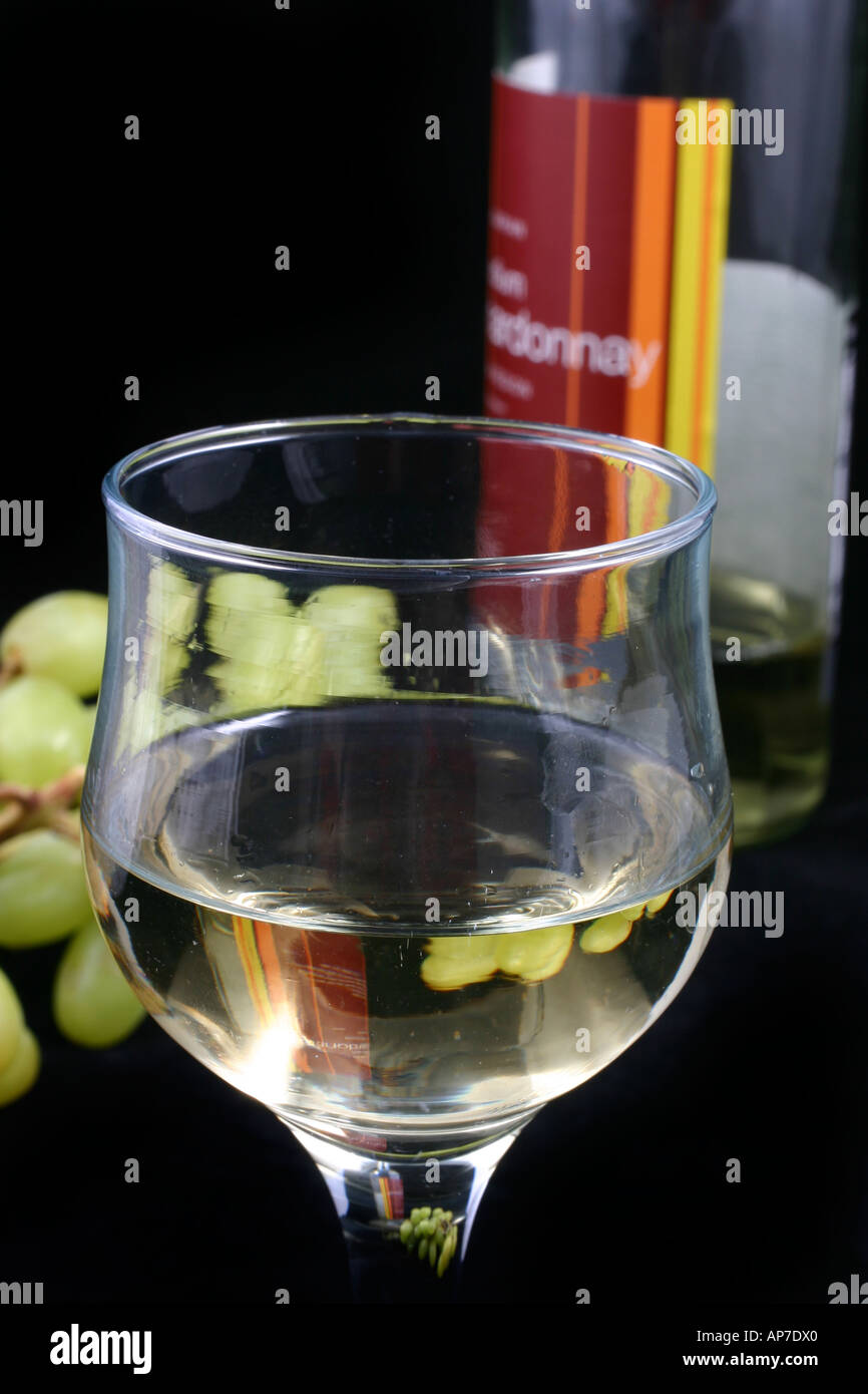 Bicchiere di vino bianco con uve e una bottiglia di vino Foto Stock