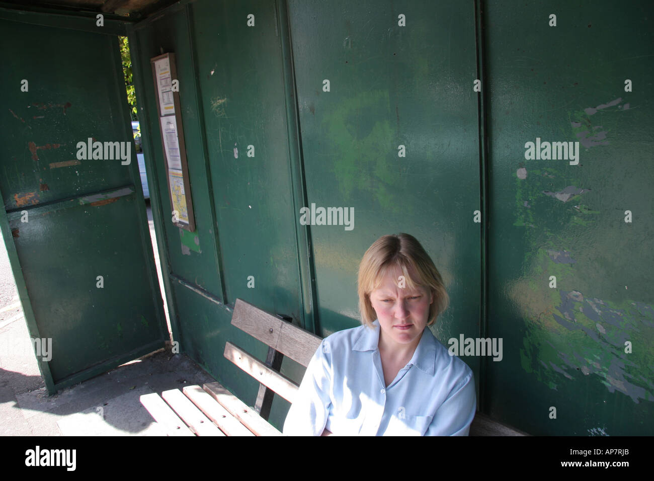 La donna in attesa alla fermata bus shelter Foto Stock