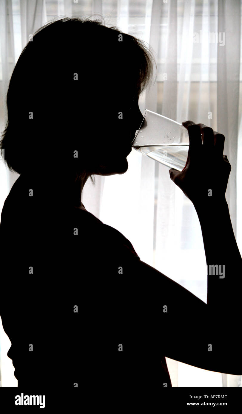 Silhouette di donna di bere un bicchiere di acqua Foto Stock