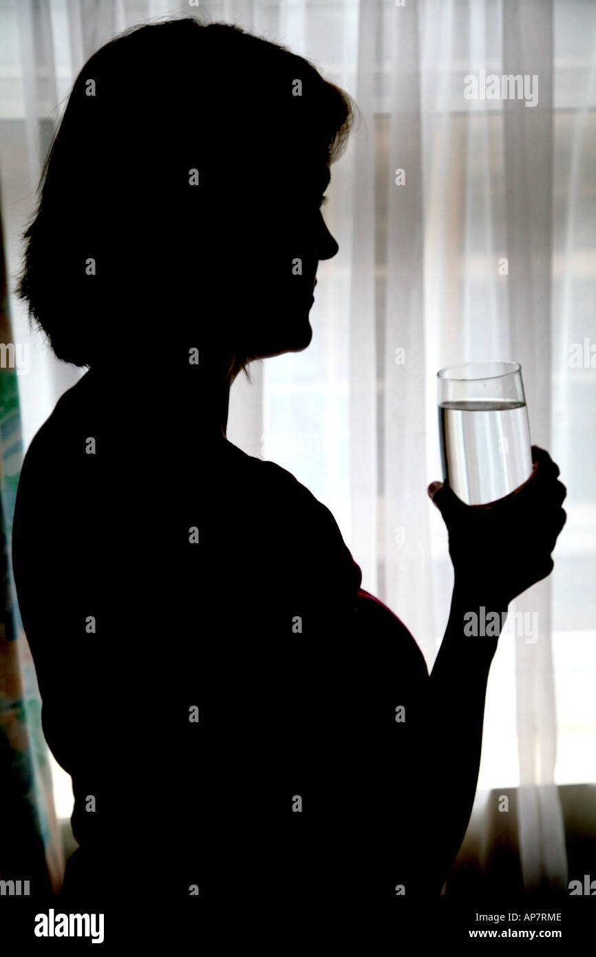 Silhouette di donna con un bicchiere di acqua Foto Stock
