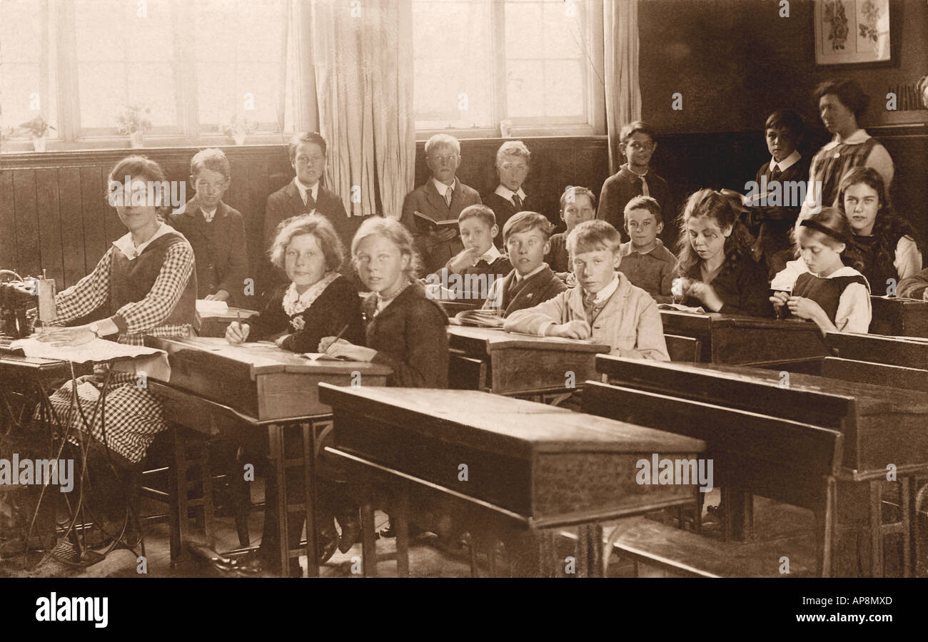 Bambini in età junior in classe a scuola primaria, con un insegnante che usa una macchina da cucire, lezione di lavoro all'ago, Cambridge, Inghilterra, UK - circa 1918 Foto Stock