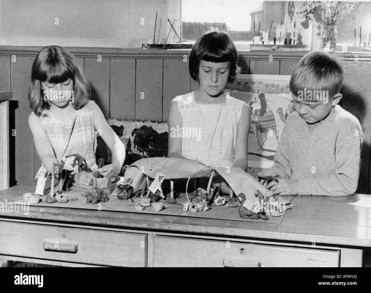 Il vecchio bianco e nero fotografia di famiglia SNAP SHOT di tre bambini rendendo i modelli in argilla a scuola del 1950 circa Foto Stock