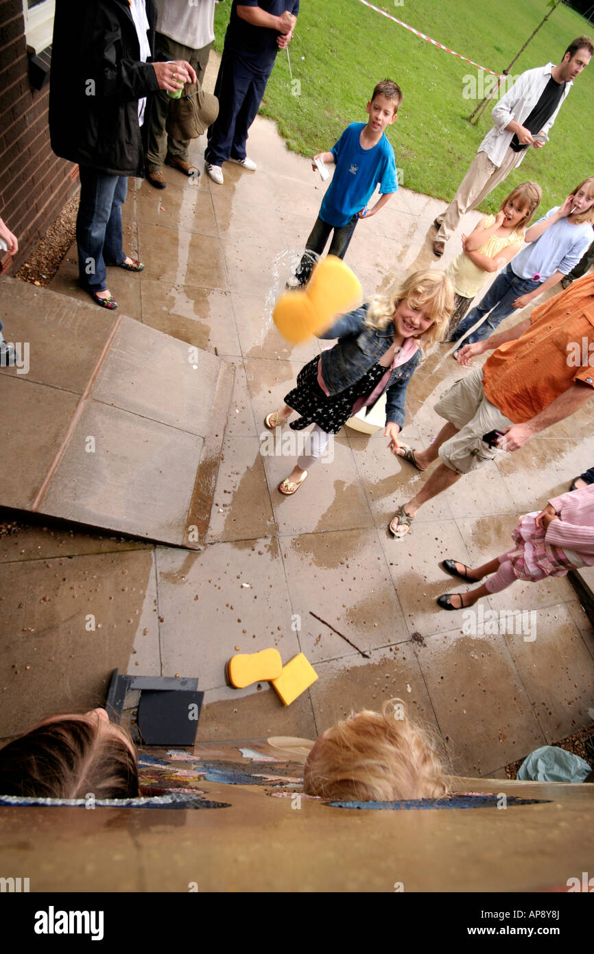 Bambini gettando spugne bagnate a persone presso una scuola fete Foto Stock