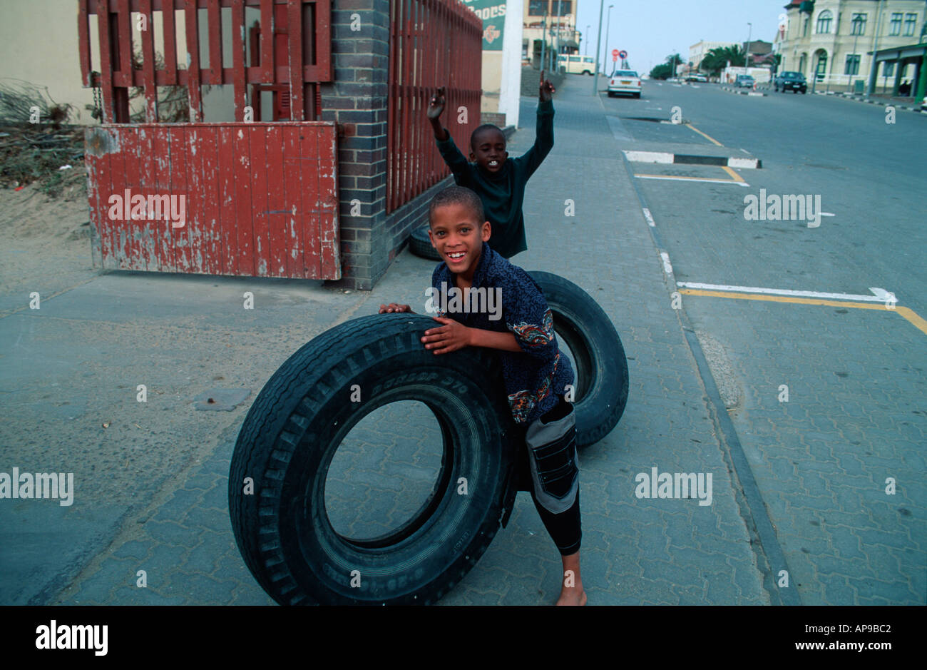 Nero ragazzi giocare con pneumatici in strada Swakopmund Namibia 2000 Foto Stock