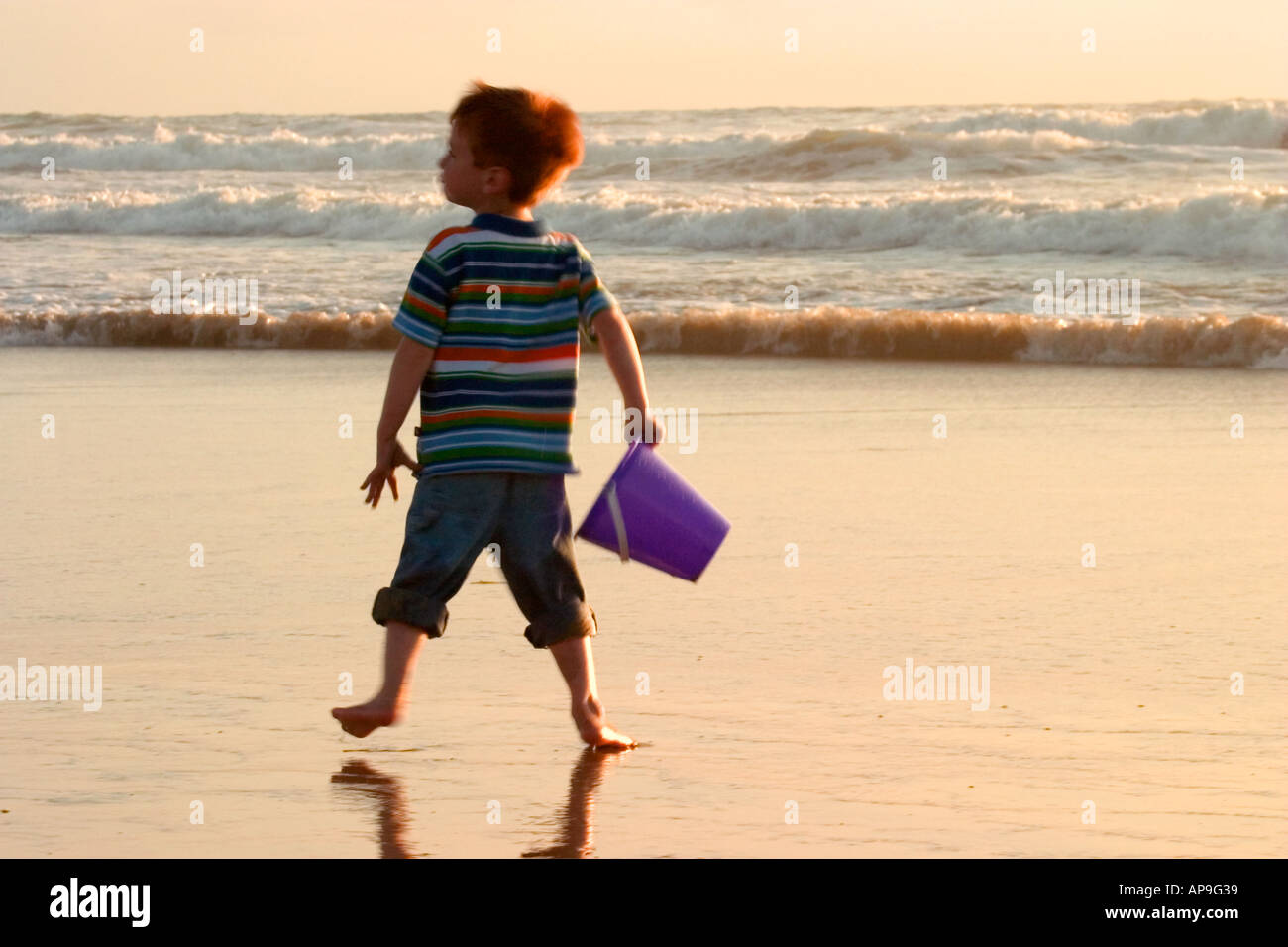 Una spensierata giovane ragazzo gioca a bordo dell'acqua presso la spiaggia. Foto Stock