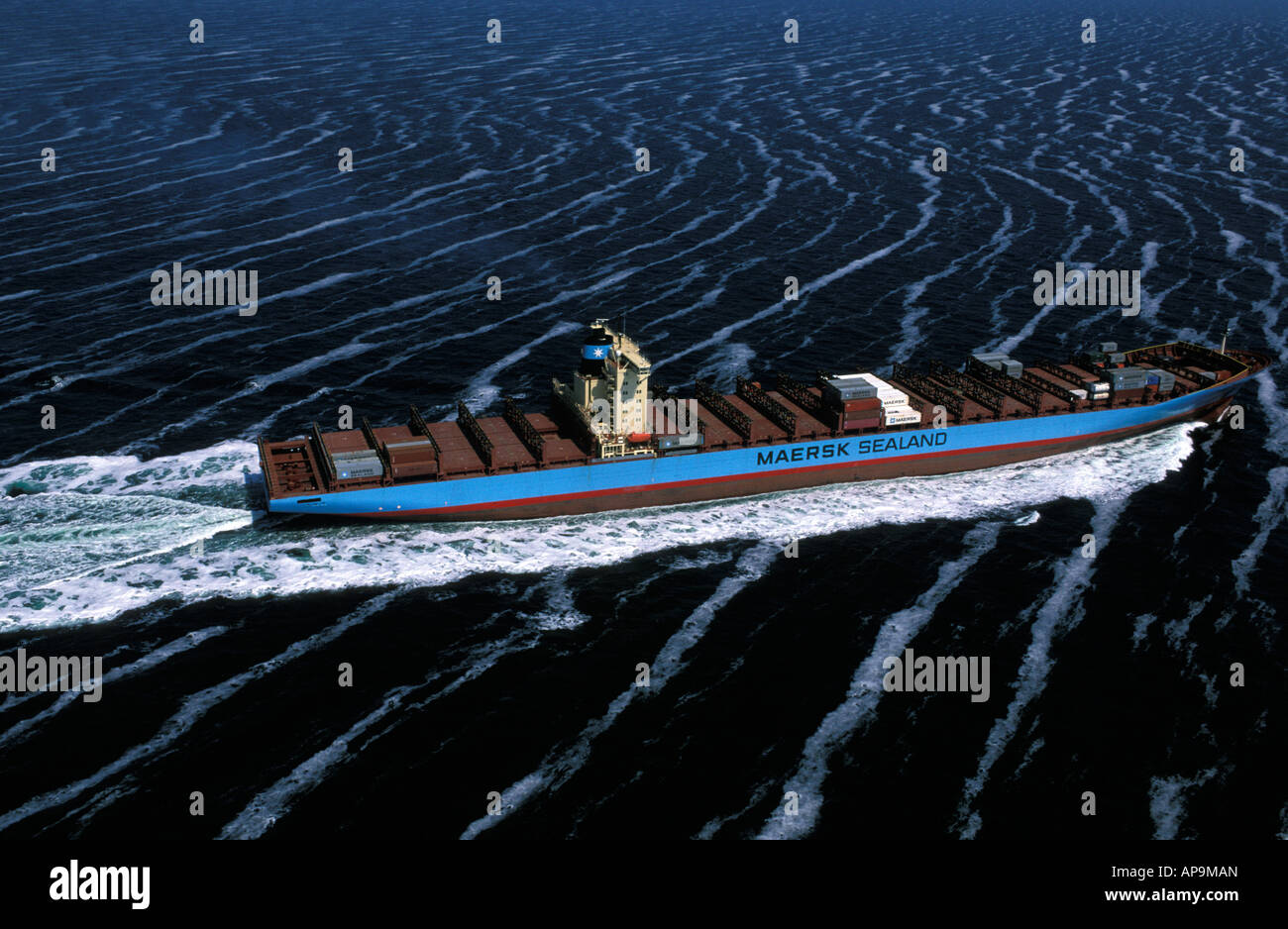 Mare del Nord un piccolo contenitore nave che naviga sul mare coperto da alghe in schiuma Foto Stock