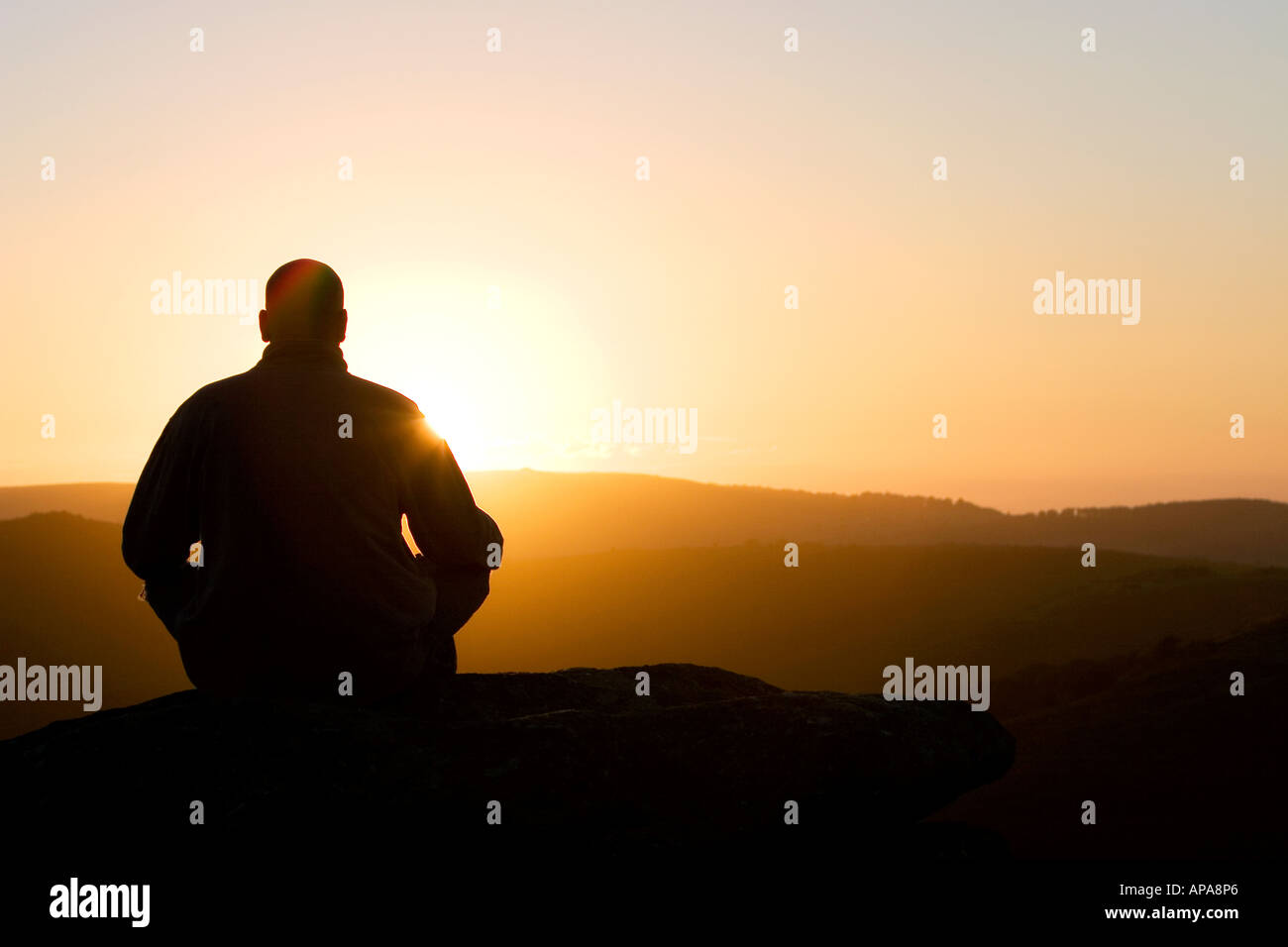 Profilo di Silhouette di un uomo seduto in meditazione su una collina di sunrise Foto Stock