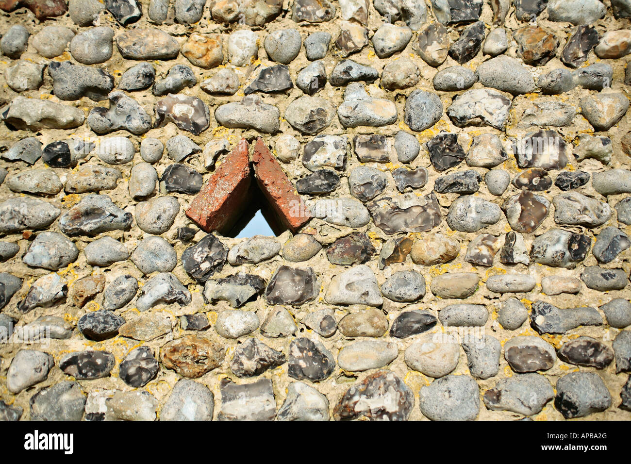 Piccola apertura triangolare in un tradizionale muro di selce del Sussex Foto Stock