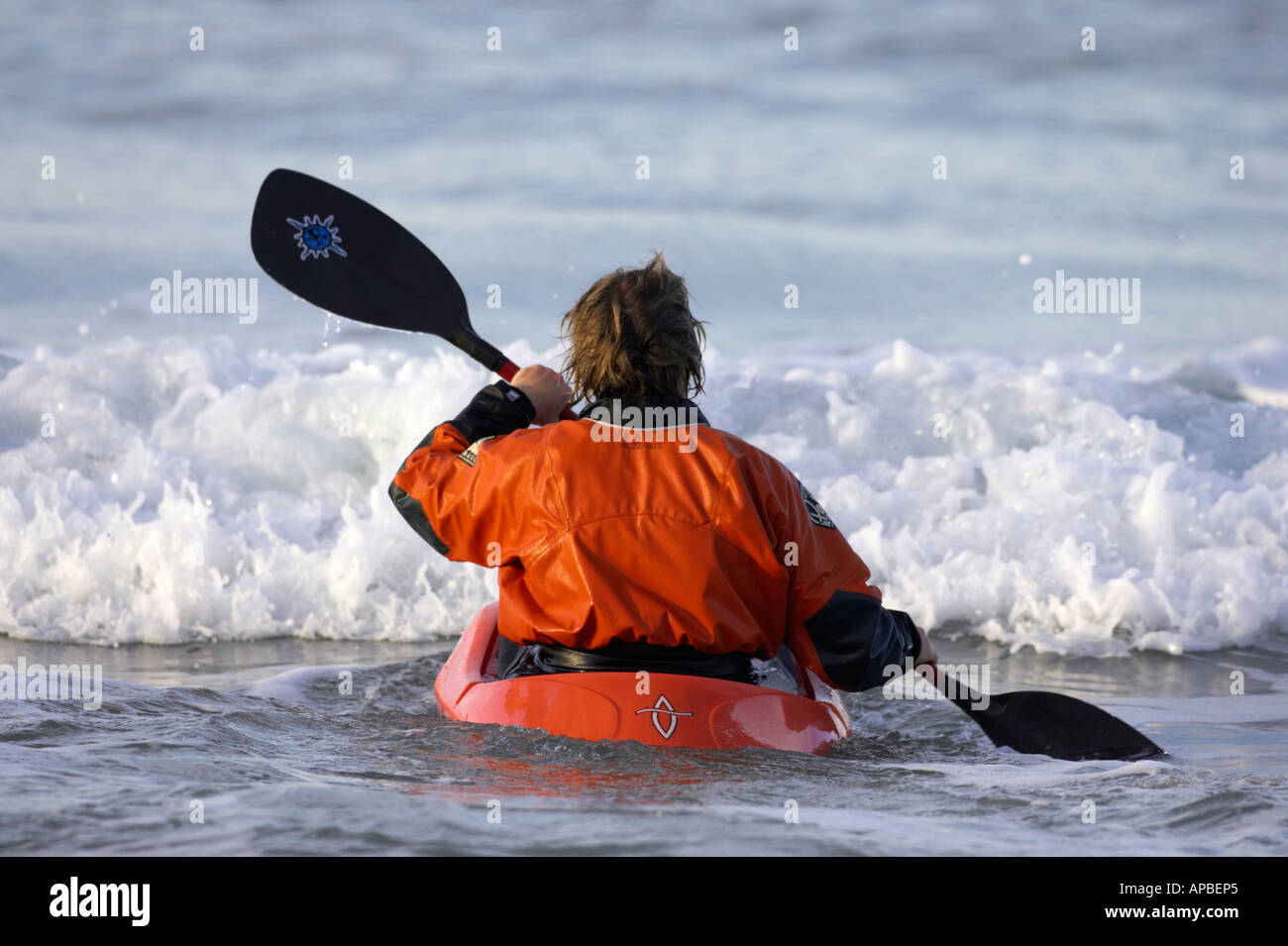 Kayaker maschio pagaie in surf dalla bianca spiaggia di rocce portrush County Antrim Irlanda del Nord Foto Stock