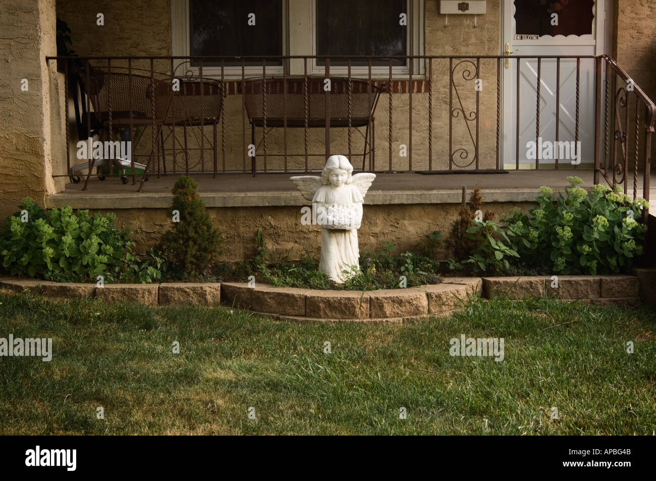 Cortile anteriore e il portico anteriore di una middle class house con un angelo statua prato ornamento di spicco nel letto di fiori Foto Stock