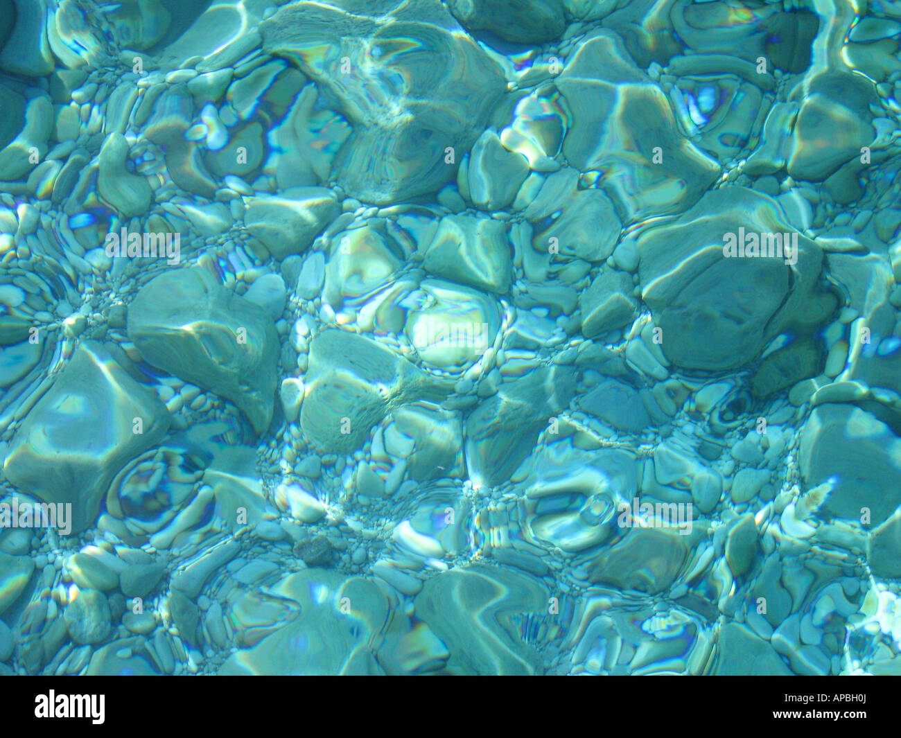 Crystal clear puro Mediterraneo con acque scintillanti di luce solare e ciottoli in fondo al mare Foto Stock
