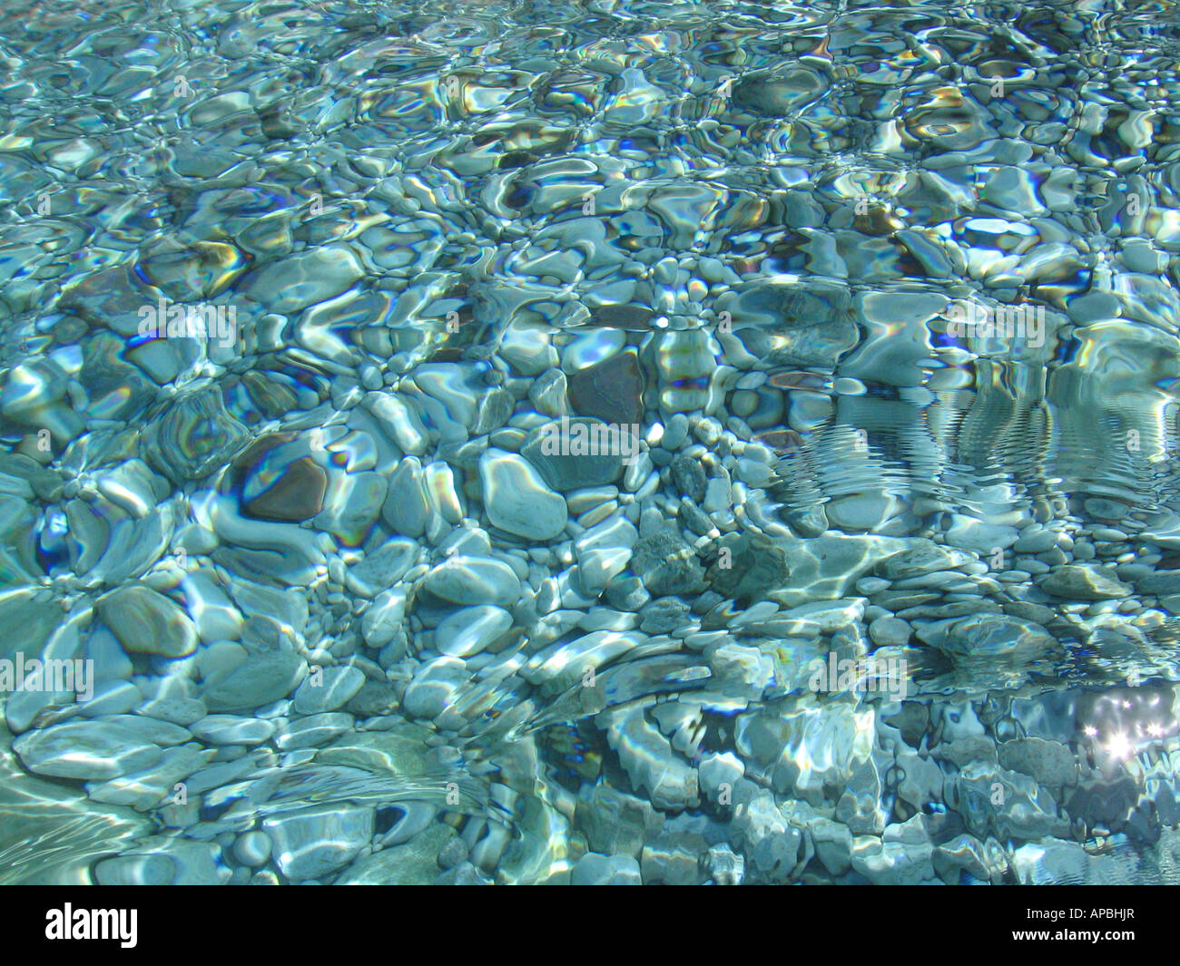 Crystal clear puro Mediterraneo con acque scintillanti di luce solare e ciottoli in fondo al mare Foto Stock