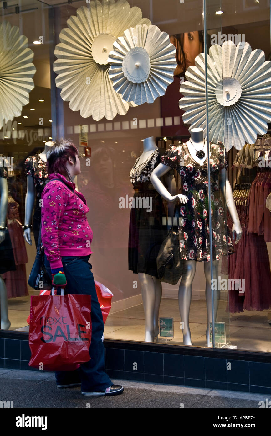 Donna ammirando abiti eleganti di fronte a un negozio di moda durante i saldi di gennaio a Dundee, Regno Unito Foto Stock