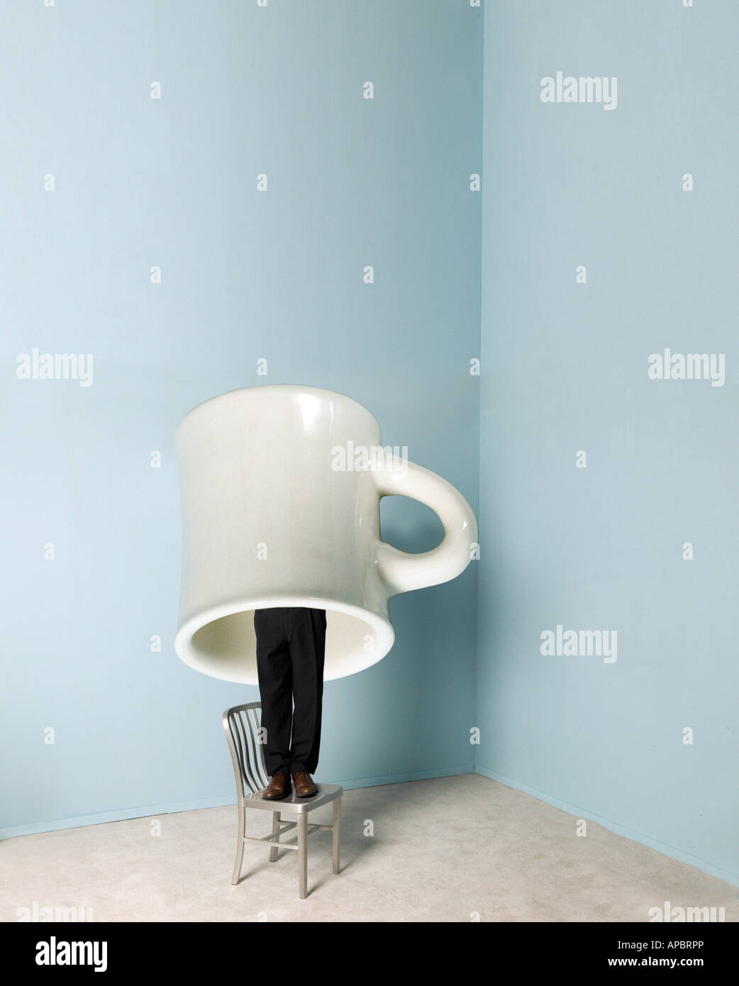 Uomo d'affari sta o nasconde sotto giganteschi tazza da caffè umorismo divertente Foto Stock