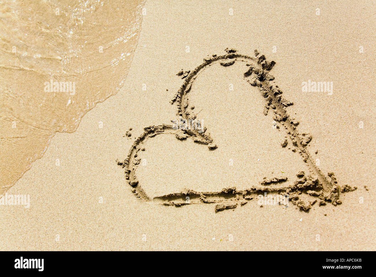 Un cuore disegnato nella sabbia di una spiaggia Foto Stock