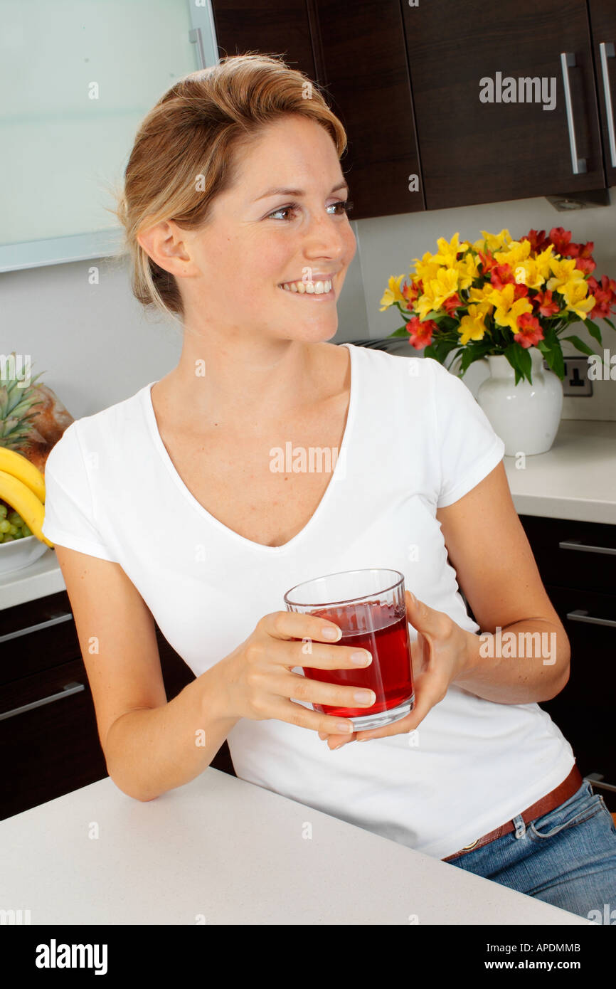 La donna in cucina a bere il succo di mirtillo palustre Foto Stock