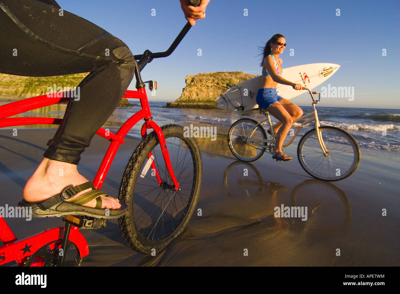 Una donna su un cruiser bike passa un uomo in un tipo di muta su un cruiser bike a ponti naturali del Parco Statale di Santa Cruz, California Foto Stock