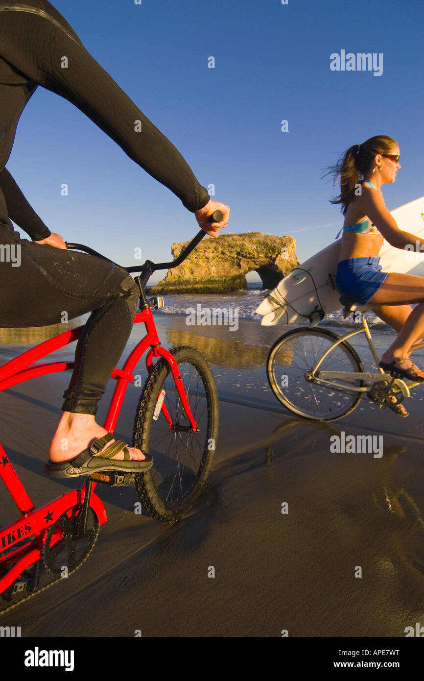 Una donna su un cruiser bike passa un uomo in un tipo di muta su un cruiser bike a ponti naturali del Parco Statale di Santa Cruz, California Foto Stock