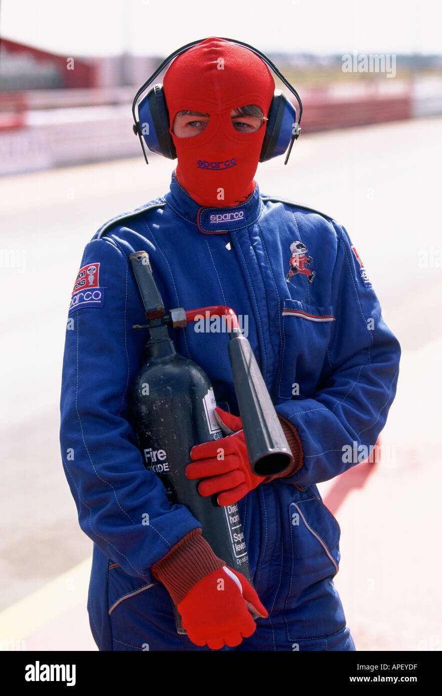 Uomo in tuta ignifuga con estintore e passamontagna sul drag strip Foto Stock